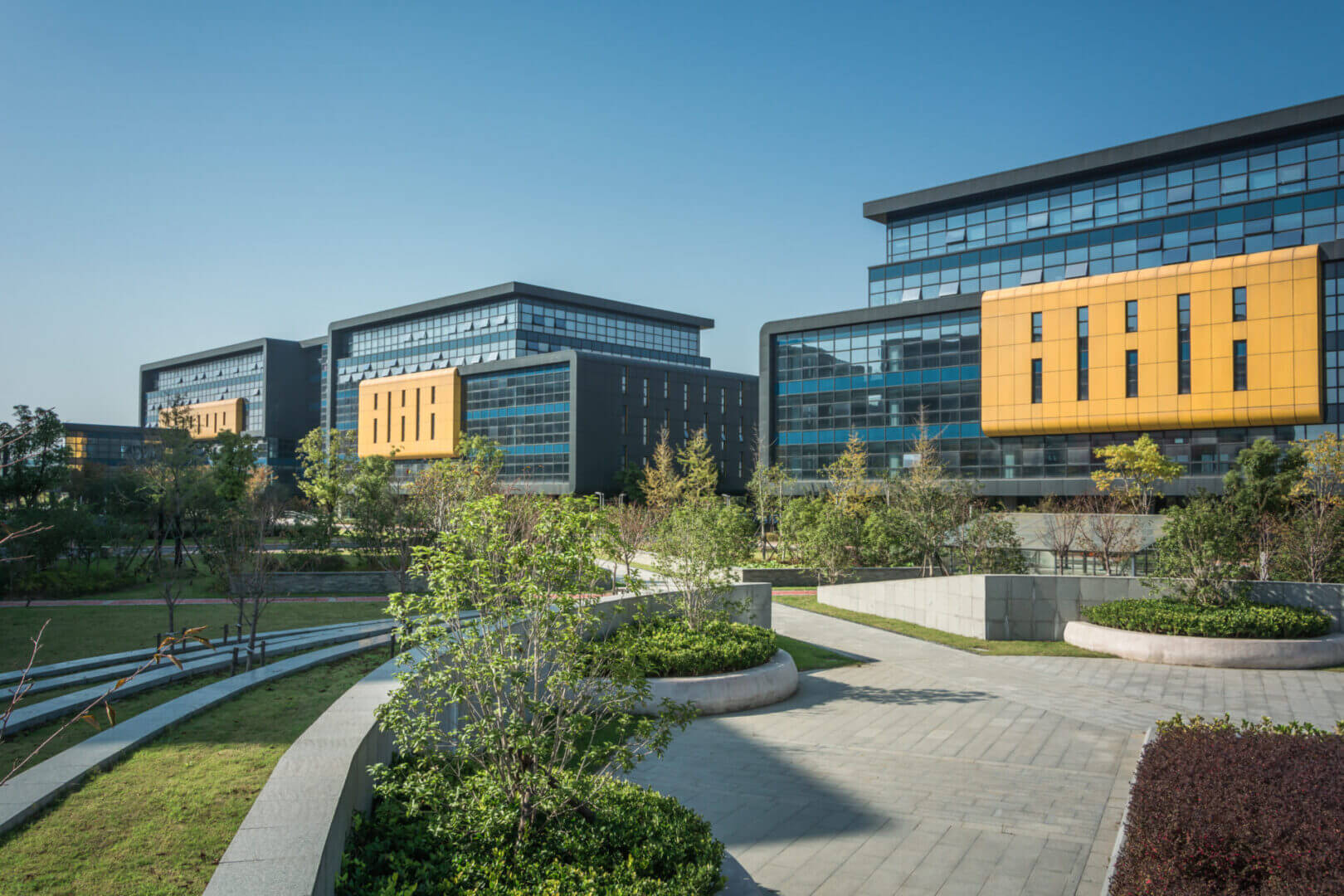 Modern office buildings with landscaped gardens and clear blue sky.