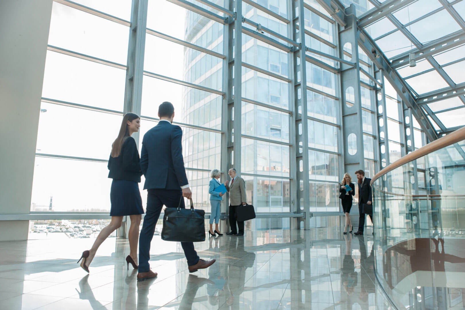 Business professionals walking in a modern glass office building lobby.