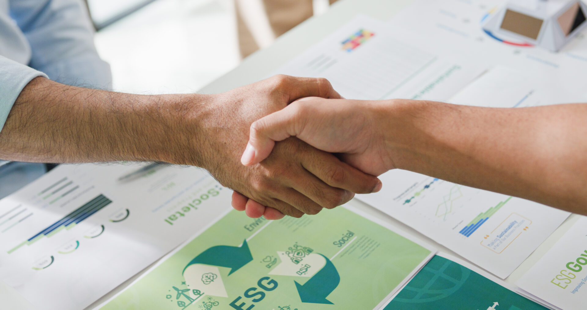 Closeup Asia businesspeople shaking hands over ESG strategic commitment workshop, SDGs report, global warming, green finance investment eco friendly and net zero waste in boardroom training building.