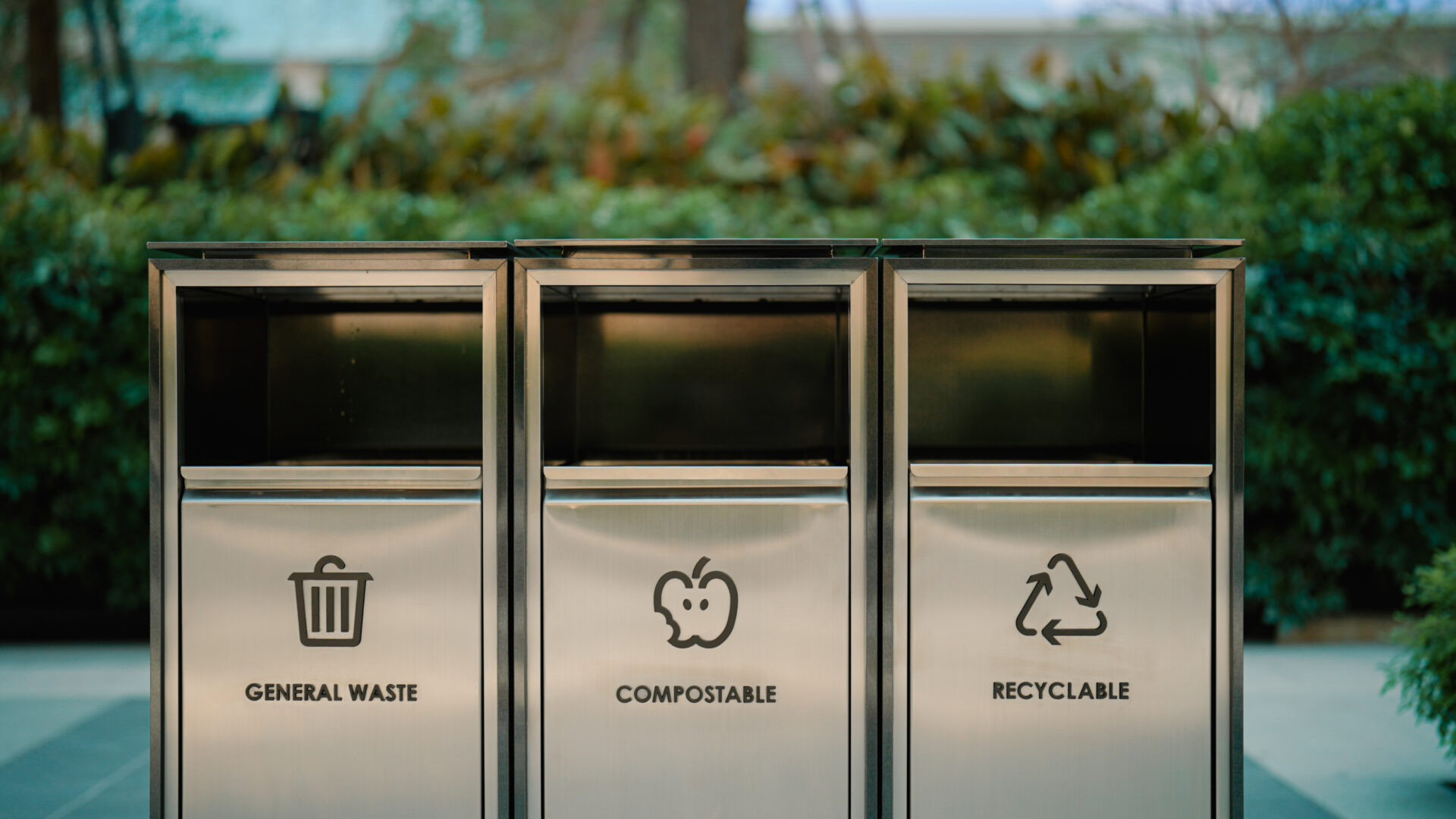 A set of waste bins being placed in an office building's common space for waste separation.