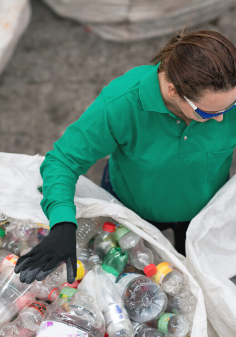 Woman working in a recycling center sorting some bottles and looking very happy - environmental concepts